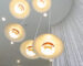 Modern overhead lighting fixture or chandelier consisting of five lights mounted in a hanging spiral at different heights from a high volume ceiling in a commercial building